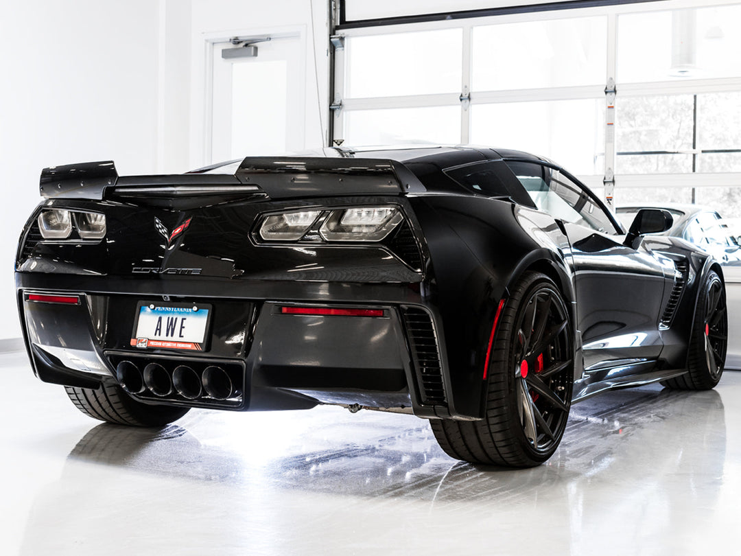 AWE Diamond Black quad exhaust tips installed on a black C7 Corvette, rear three-quarter view