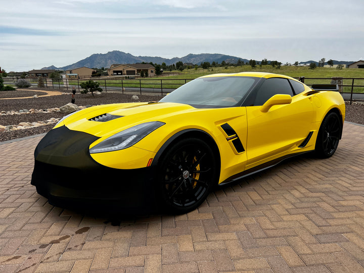NoviStretch FBM750V front bumper mask fitted to a yellow wide-body C7 Corvette, front three quarter on a brick driveway