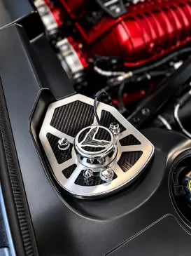 Wider view of ACC 883071 carbon-fiber and brushed stainless shock-tower trim with crossed-flag cap beside a C8 Coupe engine