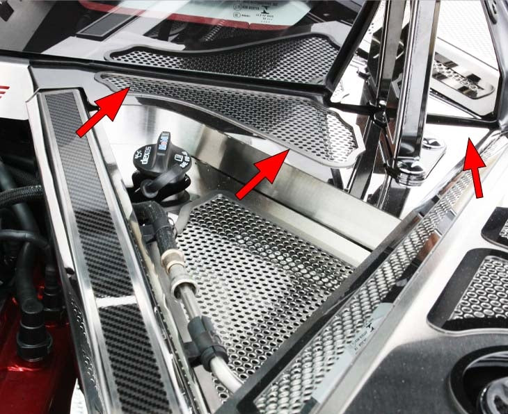 Arrows identify the perforated stainless rear cowl cover on a C8 Corvette Coupe; adjacent hinge and fender trim are separate accessories