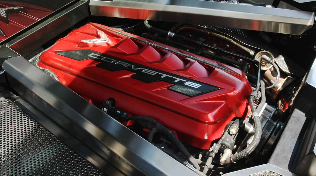 C8 Corvette Coupe engine bay with brushed stainless crossmember covers around the red engine shroud; other trim is shown for context