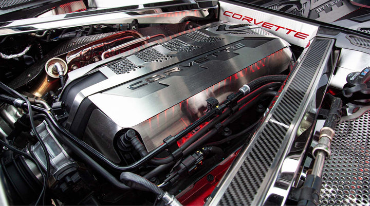 ACC 883026 carbon-fiber-topped rear crossmember cover with brushed stainless trim beside a C8 Corvette Coupe engine shroud; other dress-up parts are separate