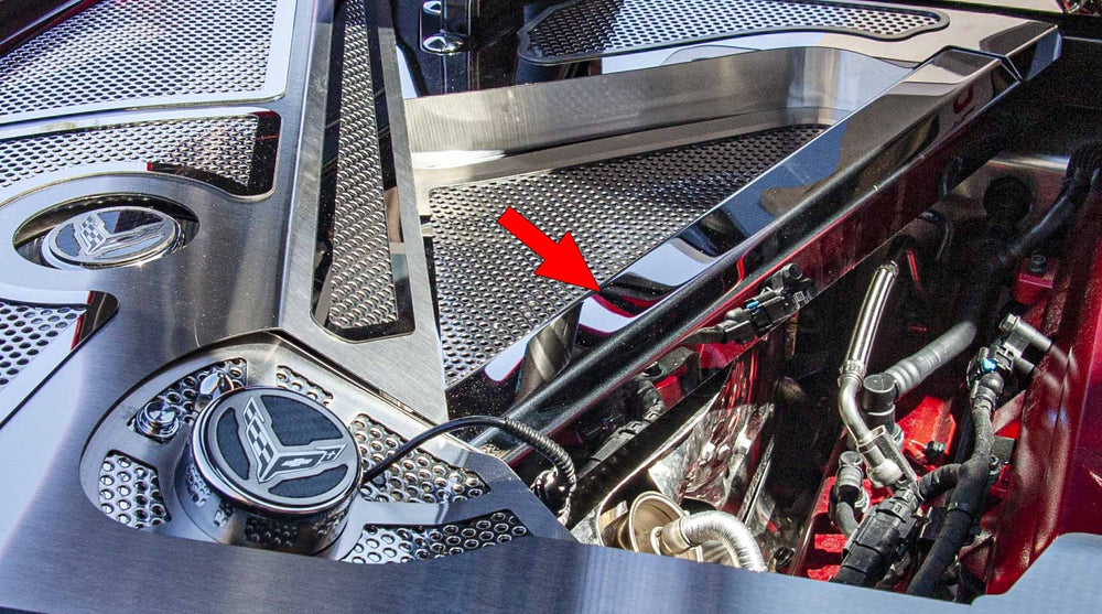 Polished stainless crossmember cover in a C8 Corvette Coupe engine bay, with an arrow marking the cover; header trim is separate