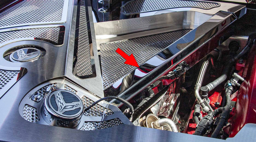 Polished stainless crossmember cover in a C8 Corvette Coupe engine bay, with an arrow marking the cover; header trim is separate