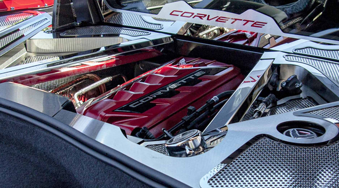 Wider view of polished stainless crossmember covers around a C8 Corvette Coupe engine bay, with separate fender and header accessories