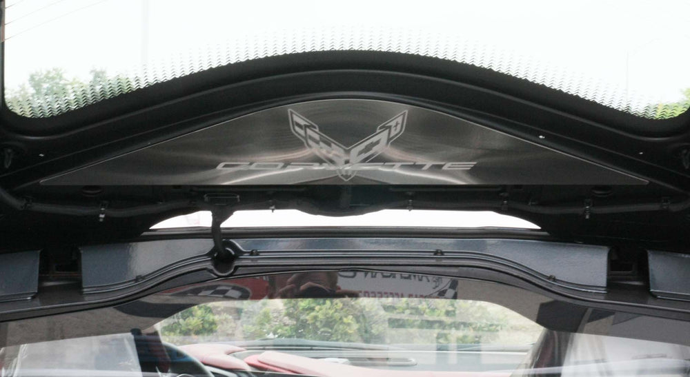 Close-up of the etched Corvette logo on ACC brushed stainless rear vanity plate 883032 beneath the rear hatch glass of a C8 Coupe