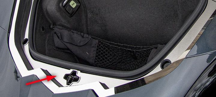 Brushed stainless frunk latch plate with polished trim installed on a C8 Corvette Coupe; arrow identifies the latch-plate area