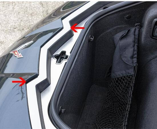 Close view of polished ACC-881012 nose-cap trim around the C8 Corvette Coupe frunk, with red arrows marking the trim