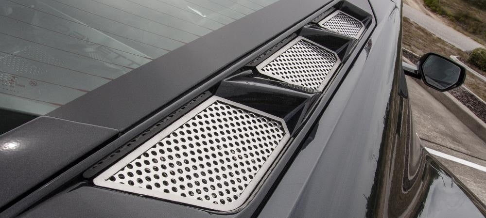 Angled view of three polished stainless rear hood vent inserts beside the C8 Corvette Coupe rear window