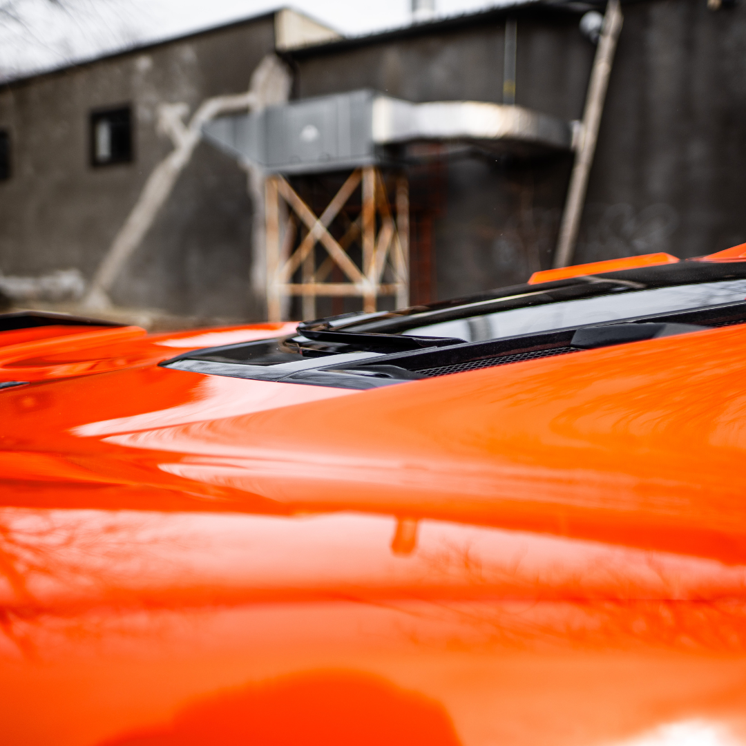 ACS Composite rear window spoiler on an orange narrow-body C8 Corvette photographed outdoors, showing the finished edge along the glass