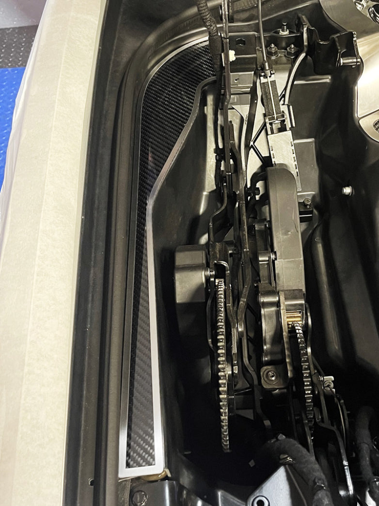 Carbon fiber hinge dress-up plate with brushed stainless trim beside one C8 convertible hinge mechanism