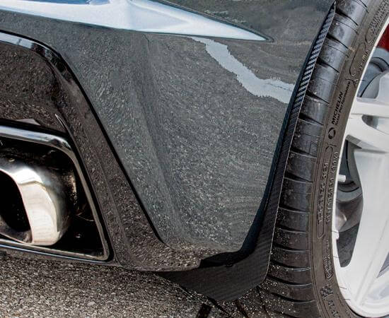 Carbon-fiber-wrapped rear mud guard beside the rear wheel of a C8 Corvette, shown close up with the surrounding bodywork