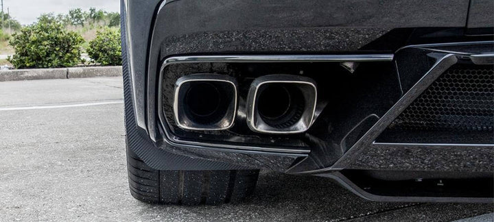 Left rear carbon-fiber-wrapped mud guard on a C8 Corvette, viewed behind the wheel beside the exhaust and lower body panel
