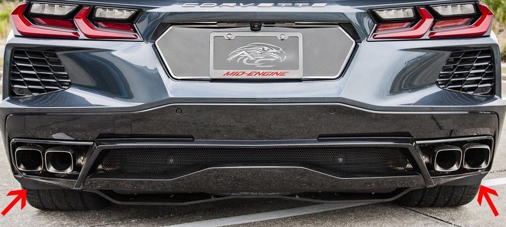 Rear view of a C8 Corvette with arrows marking both carbon-fiber-wrapped rear mud guards; other rear accessories are shown