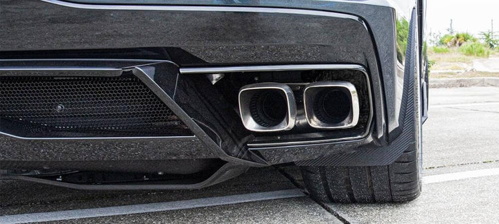 Right rear carbon-fiber-wrapped mud guard on a C8 Corvette, viewed behind the wheel with the rear bumper and exhaust in view