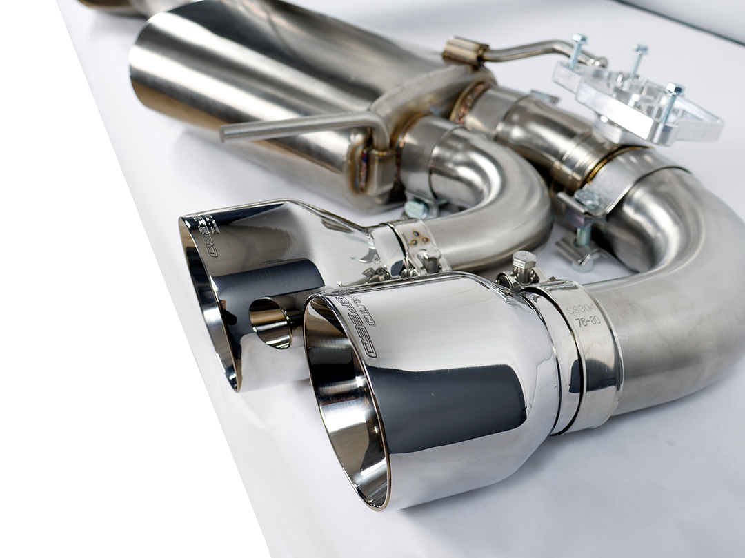 Rear three quarter view of the AutoSpeed cat-back on a studio table, all four polished quad tips in frame